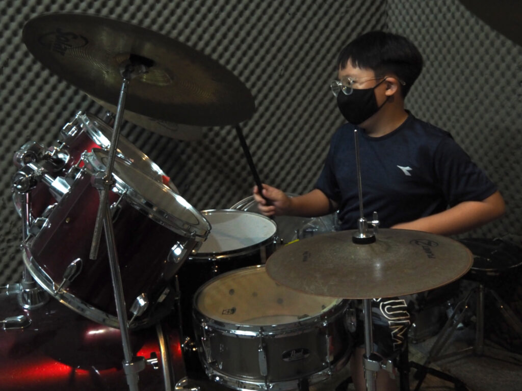 Student playing full drum kit during lesson