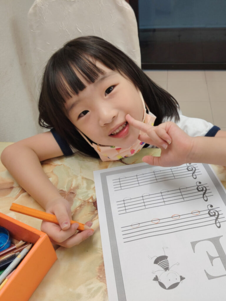 Child student smiles towards camera while doing music theory