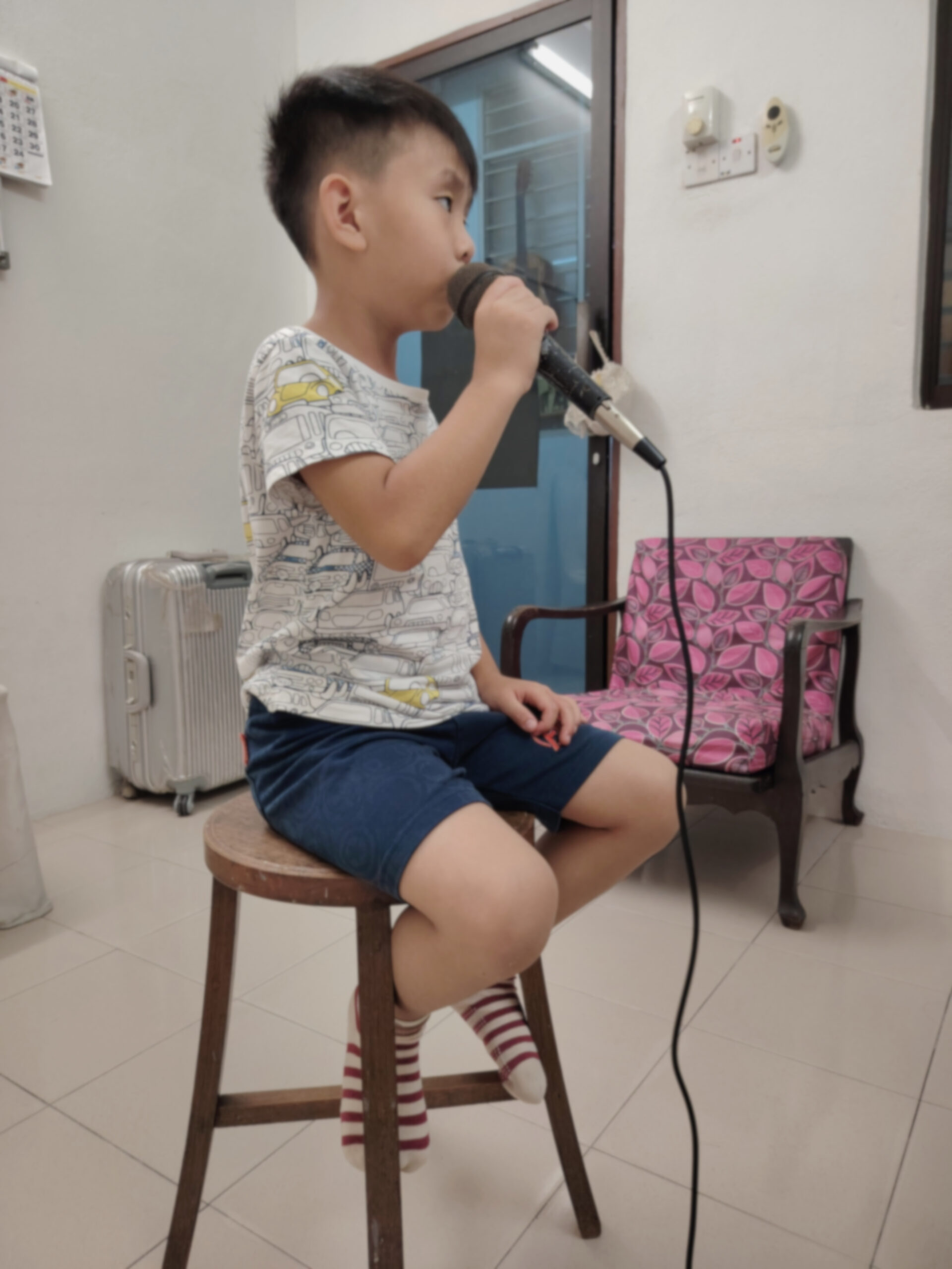 Child student sitting singing into mic during class
