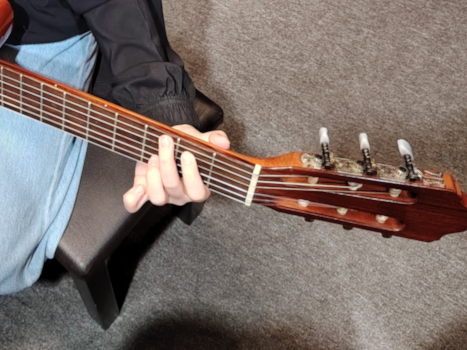 Person demonstrating proper finger placement on guitar frets