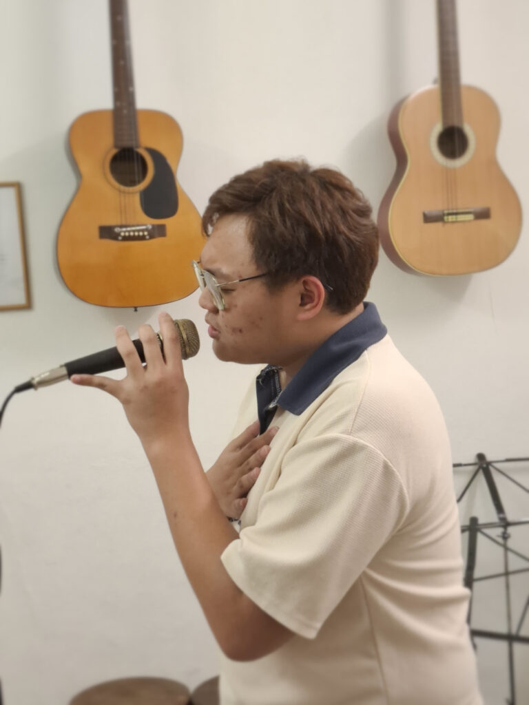 An adult singing expressively into a microphone during a class