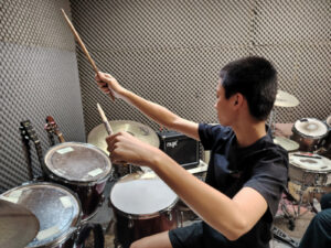 Student performing expressively in front of drum kit